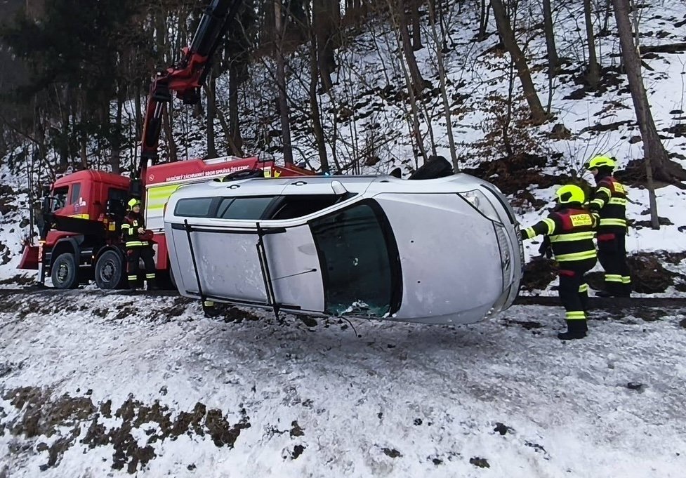 Auto sklouzlo ze silnice přímo ke kolejím, pro zraněného museli hasiči do svahu